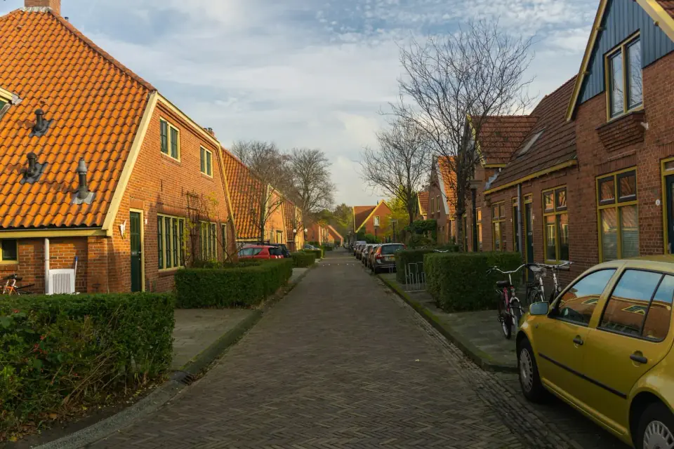 Een Nederlandse woonstraat met klinkers en rijtjeshuizen van rode baksteen met oranje pannendaken